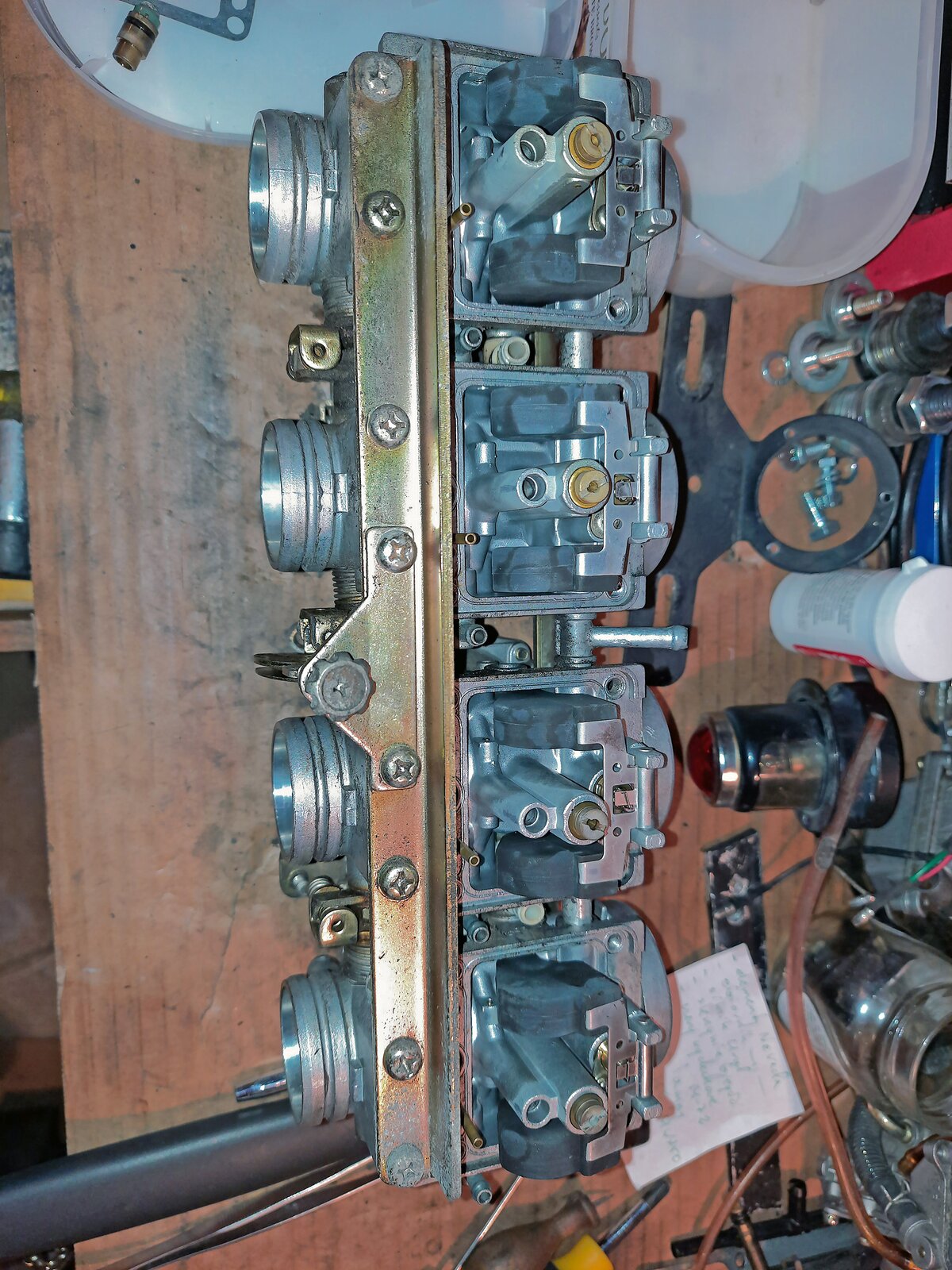 Na ekranie przedstawiono zestaw czterech gaźników ze zdemontowanymi pokrywami komór pływakowych.