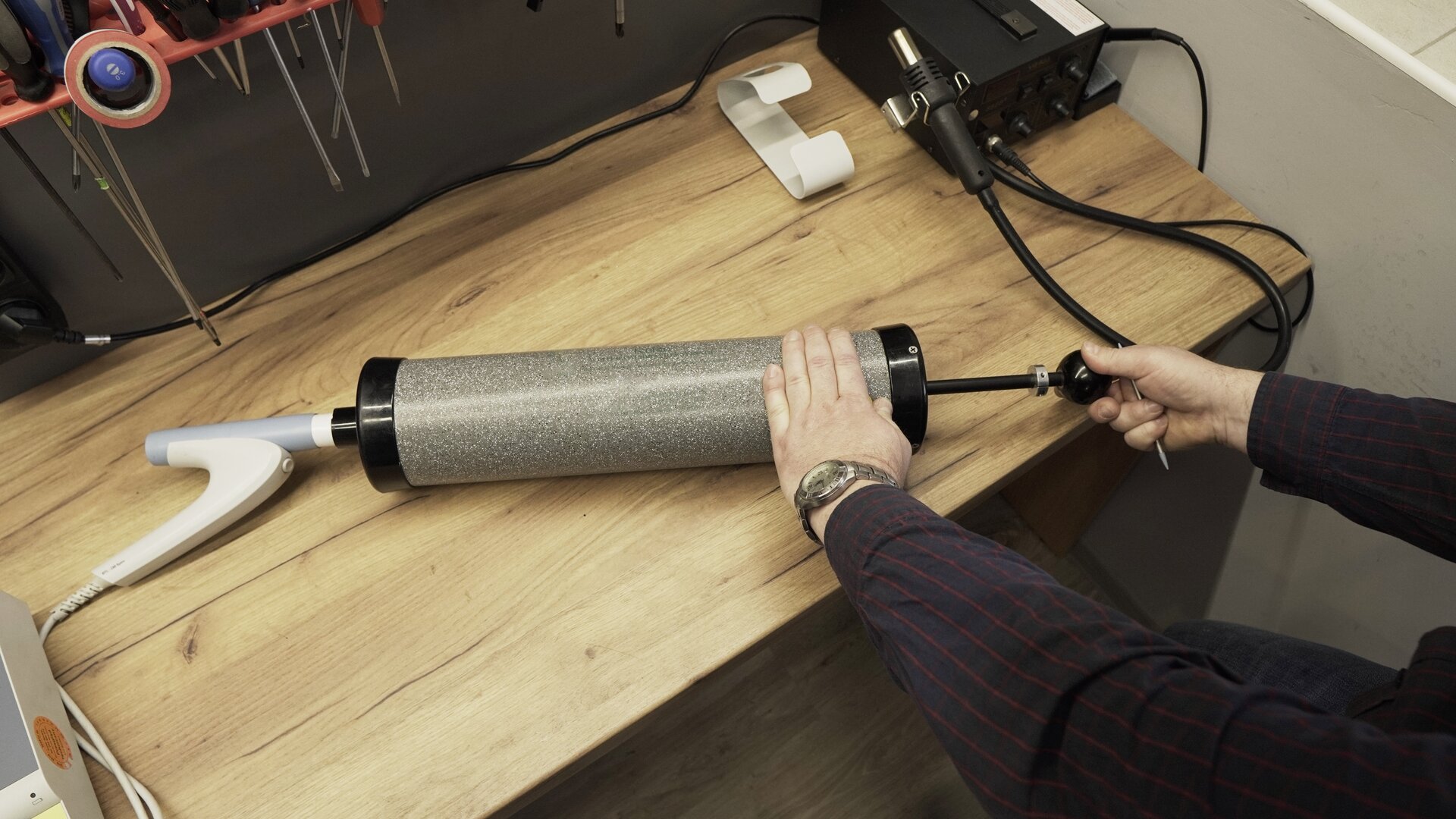 Na zdjęciu technik cewą ręką przytrzymuje tubę pompy, druga znajduje się na rękojeści częściowo wysuniętego tłoka.