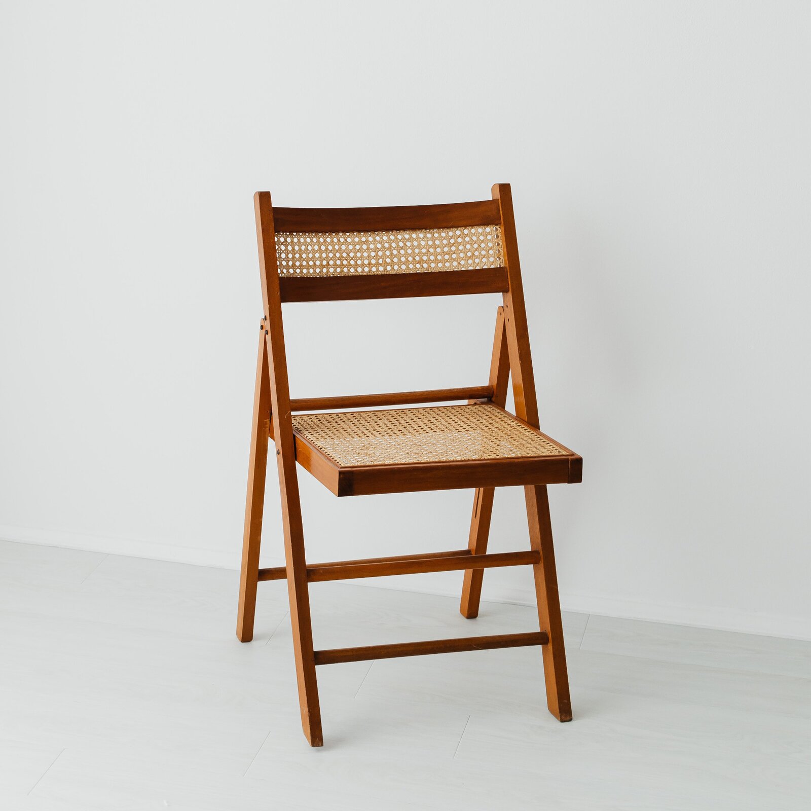 Ilustracja przedstawia drewniane  krzesło. Krzesło jest składane.