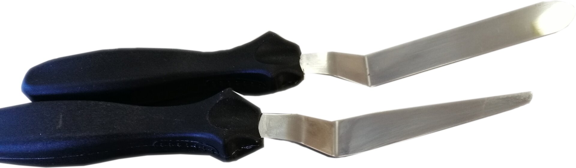 Zdjęcie przedstawia szpatułki kątowe. Widoczne są dwie szpatułki w poziomie. Po lewej stronie widoczne są czarne rękojeści, w których osadzone są metalowe części robocze tuż przy nasadzie kolankowato wygięte. Części robocze na końcu zwężają się.