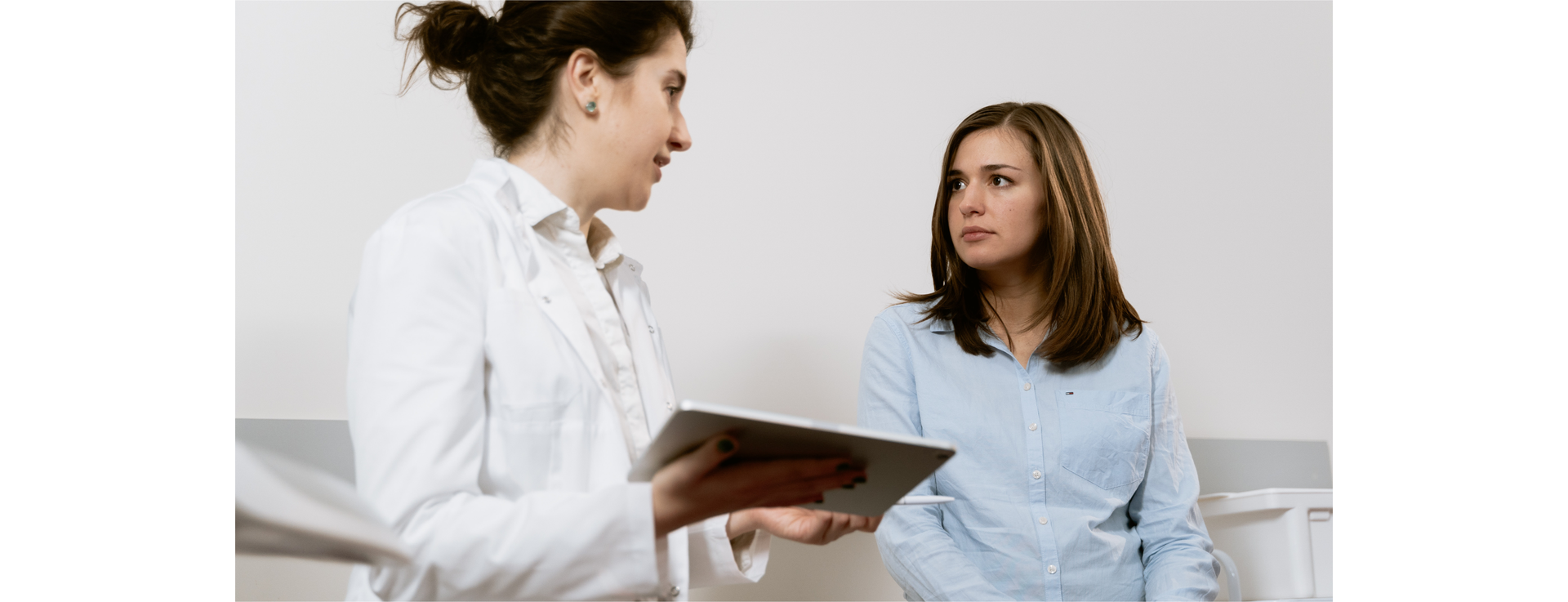 Zdjęcie przedstawia dwie kobiety, które są zwrócone ku sobie. Jedna z nich trzyma w ręku tablet.