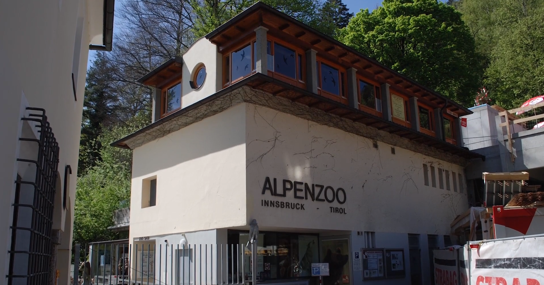 Scena przedstawia budynek, na którym pojawia się napis: Alpenzoo. Następnie pojawiają się zdjęcia rybek w akwarium, wilka i niedźwiedzia.