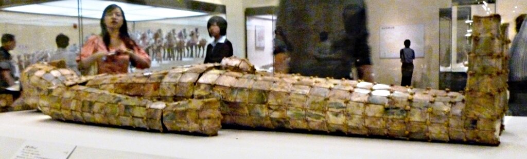 Zdjęcie przedstawia nefrytowy strój pogrzebowy z I w. p.n.e. Okrywa on manekina. Jest przygotowany z wielu prostokątnych elementów, połączonych ze sobą. 