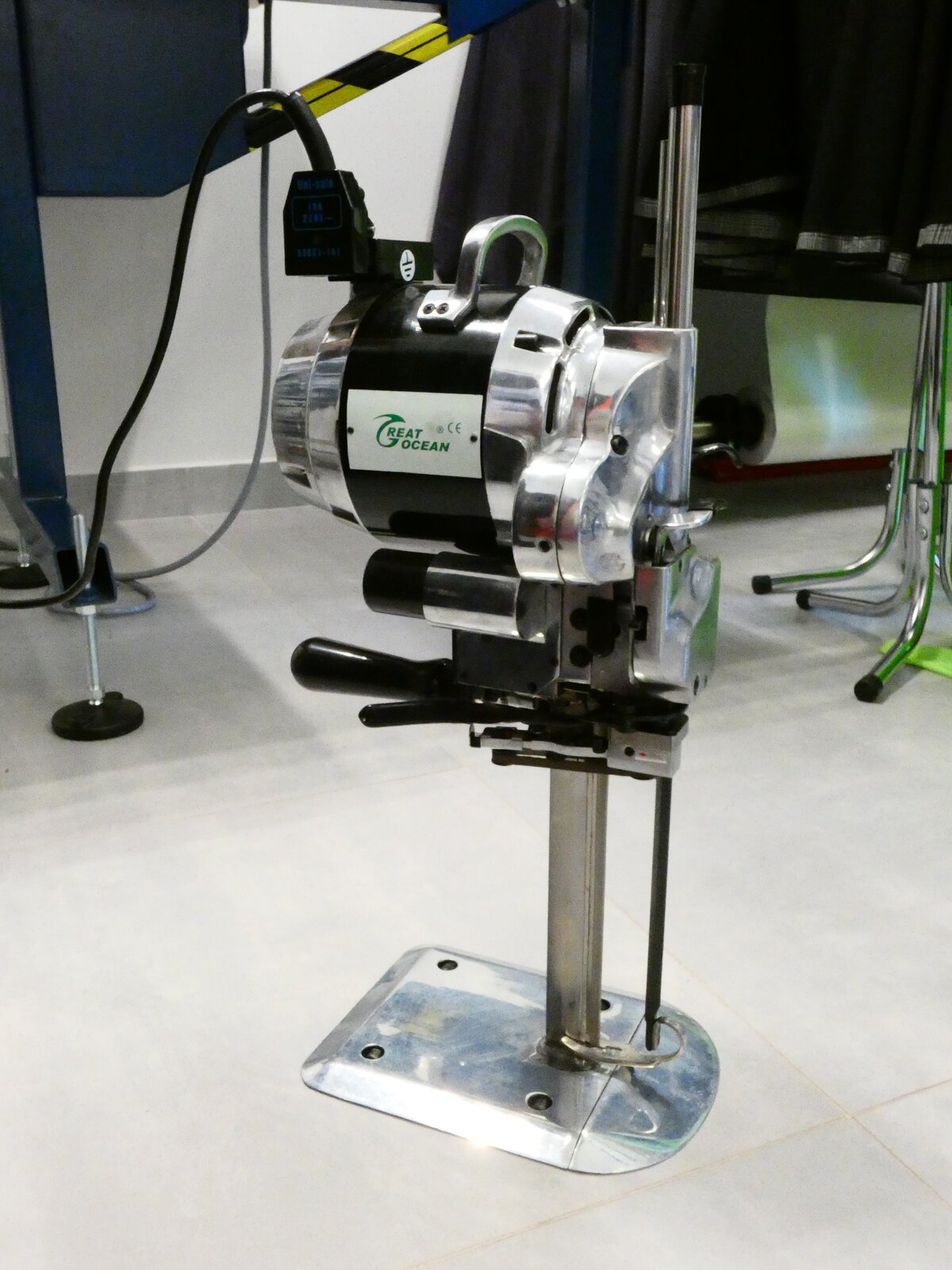 Zdjęcie przedstawia metalowe urządzenie. Jest postawione na podłodze, składa się z mechanizmu u góry o obłym kształcie, z napisem, oraz szerokiej podstawy. 