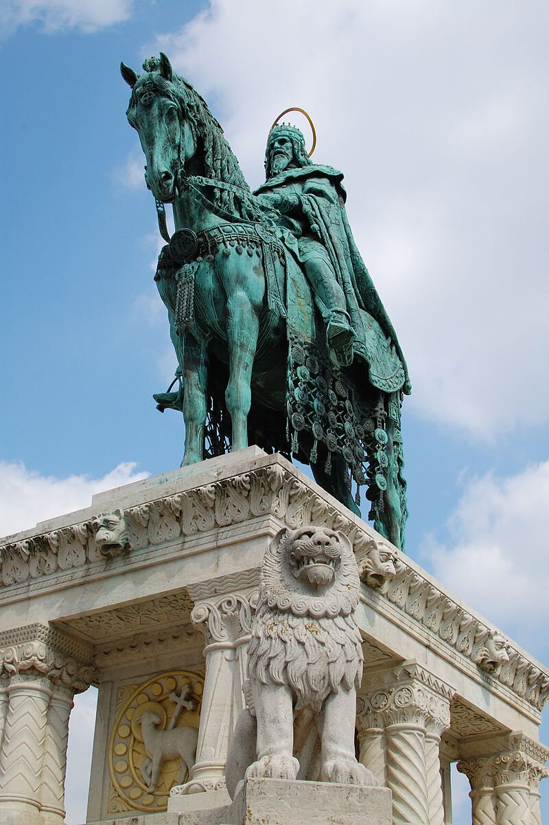 Zdjęcie przedstawia postument z pomnikiem. To mężczyzna w królewskim stroju i koronie, siedzący na koniu.