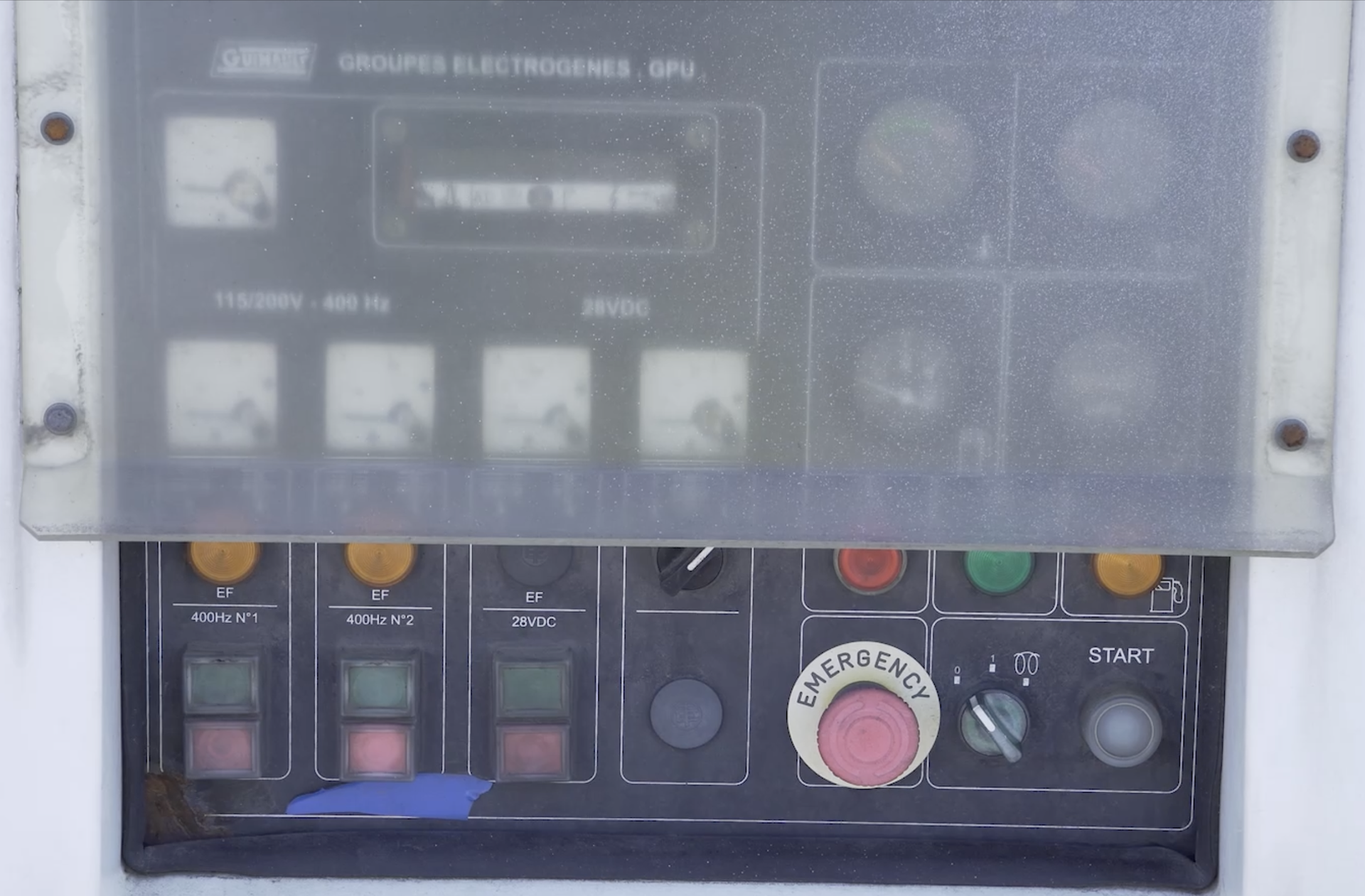 Zdjęcie przedstawia tylną ścianę G P U, czyli agregatu prądotwórczego zasilany paliwem. Na ścianie znajduje się panel sterowania z wieloma przyciskami.