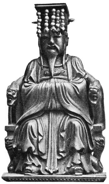 Zdjęcie przedstawia pomnik mężczyzny o skośnych oczach. Mężczyzna siedzi. Ma spiczastą bródkę. Ubrany jest w długą szatę. Ma nakrycie głowy, z którego zwisają rzędami ozdobne elementy w kształcie kulek.   