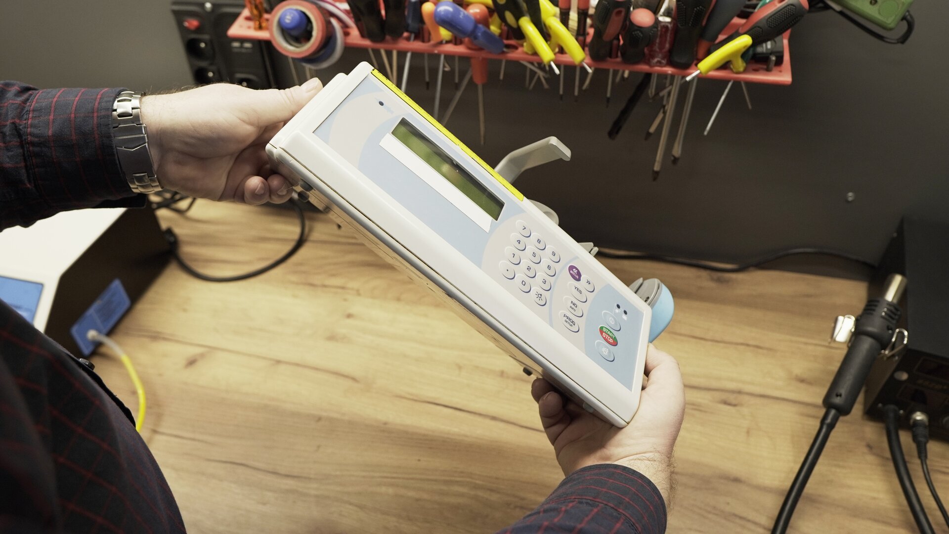 Na zdjęciu technik przeprowadza test wizualny pompy infuzyjnej. Ogląda obudowę aparatu.  