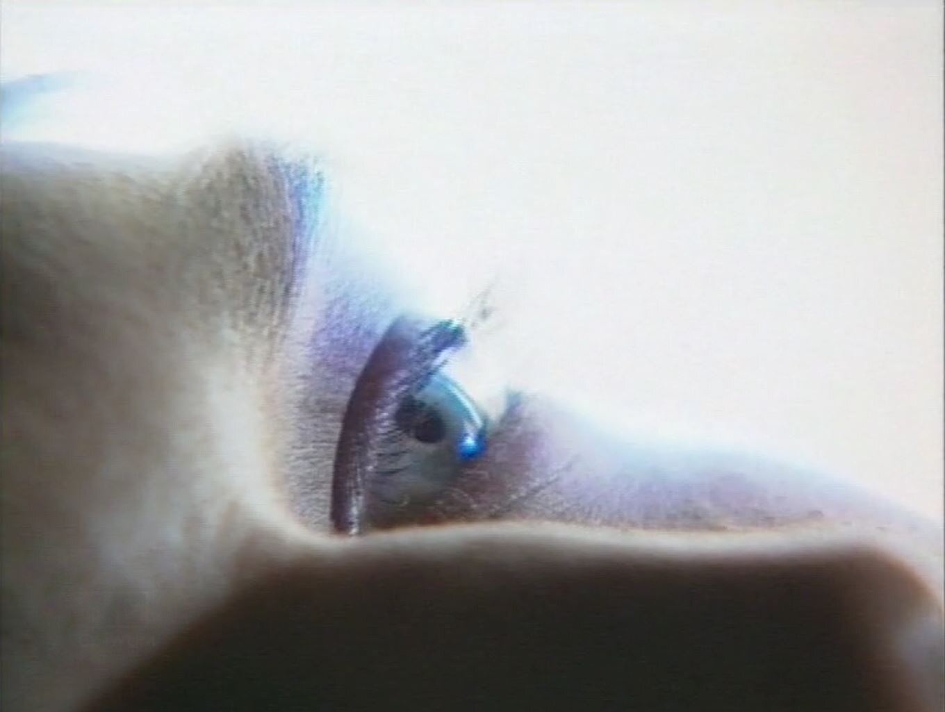 Zdjęcie przedstawia kadr z filmu. Ukazany jest fragment twarzy młodej kobiety w dużym zbliżeniu. Najlepiej widoczne jest jej otwarte oko.