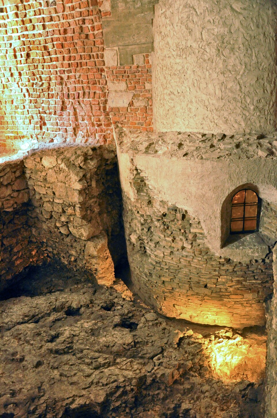 Ilustracja o kształcie pionowego prostokąta przedstawia fragment rotundy św. Feliksa i Adaukta na Wawelu. Zdjęcie zostało wykonane podczas prac konserwatorskich. Przedstawia odsłonięte fragmenty dolnej części murów, wykonanych z kamienia. Wyższe partie muru wykonane są z czerwonej cegły. U dołu znajduje się podzielone na cztery części małe okno, zamknięte od góry łukiem.  