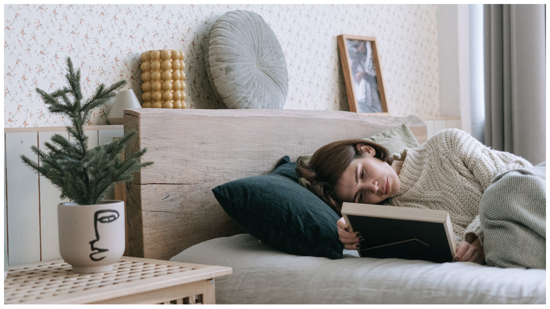 Ilustracja przedstawia kobietę leżącą w łóżku, która ogląda zdjęcie w ramce.