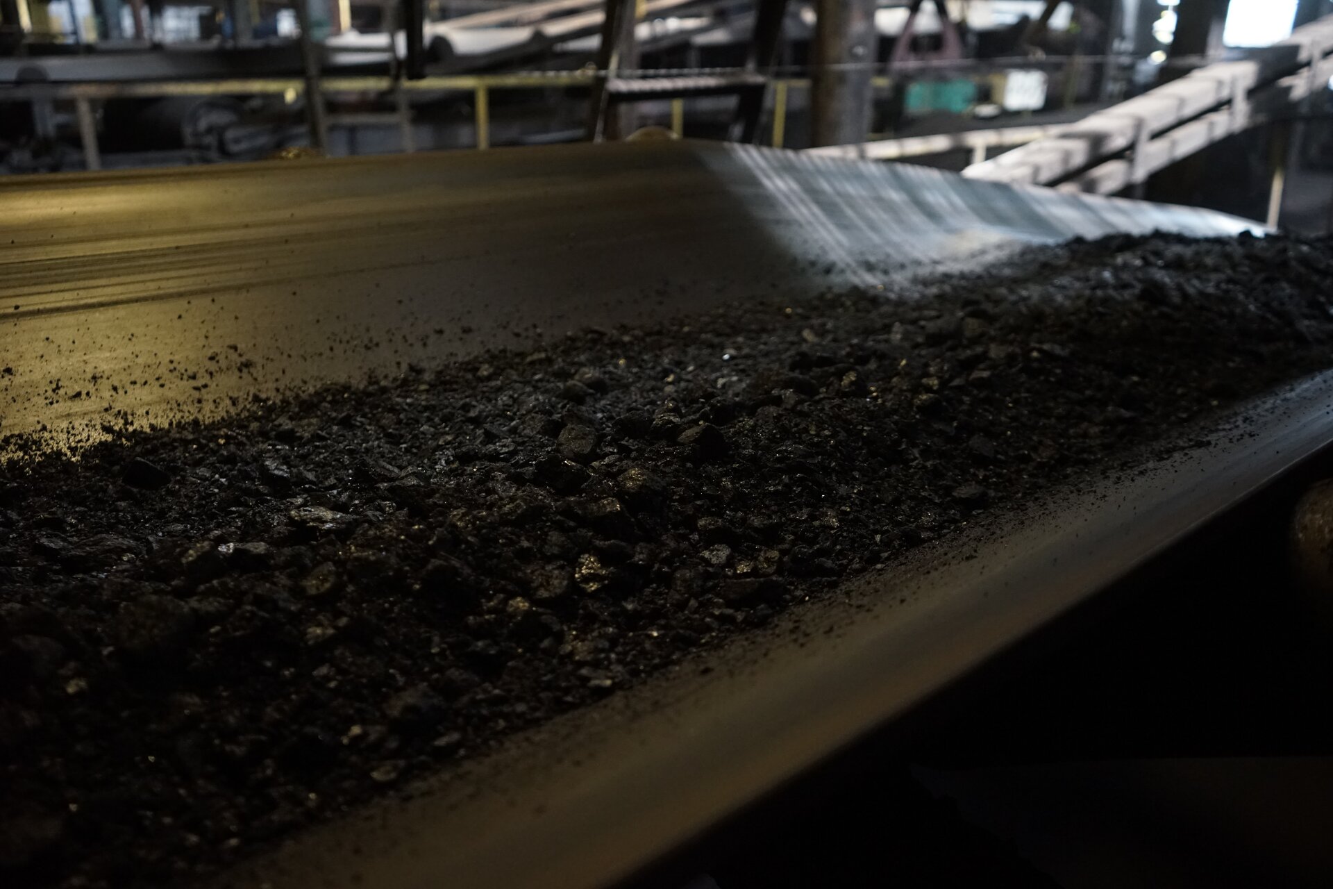 Zdjęcie przedstawia taśmę przenośnika. Transportowane są nią rozdrobnione ziarna węgla. Po prawej stronie widoczny jest spadek taśmy, dzięki konstrukcji transport może być prowadzony również pod pewnym kątem względem płaszczyzny poziomej. Poniżej zdjęcia znajduje się przycisk multimedialny z nagraniem audio. Treść nagrania jest zgodna z tytułem zdjęcia.