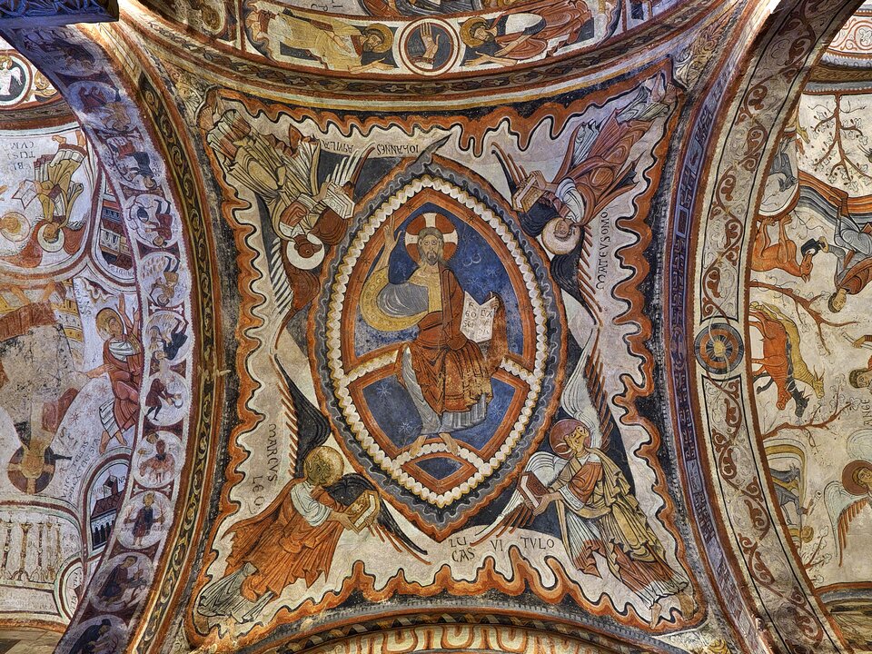 Sklepienie romańskie pokryte bogatymi średniowiecznymi freskami. W centrum znajduje się Chrystus w mandorli, siedzący frontalnie i trzymający księgę, otoczony symbolami czterech ewangelistów w postaci uskrzydlonych postaci. Wokół, na łukach i polach sklepienia, rozmieszczone są liczne sceny figuralne i ornamentalne z motywami biblijnymi, zwierzęcymi i roślinnymi. Kompozycja utrzymana jest w ciepłych barwach ochry, czerwieni i błękitu, z wyraźną fakturą tynku i śladami wielowiekowego postarzenia.
