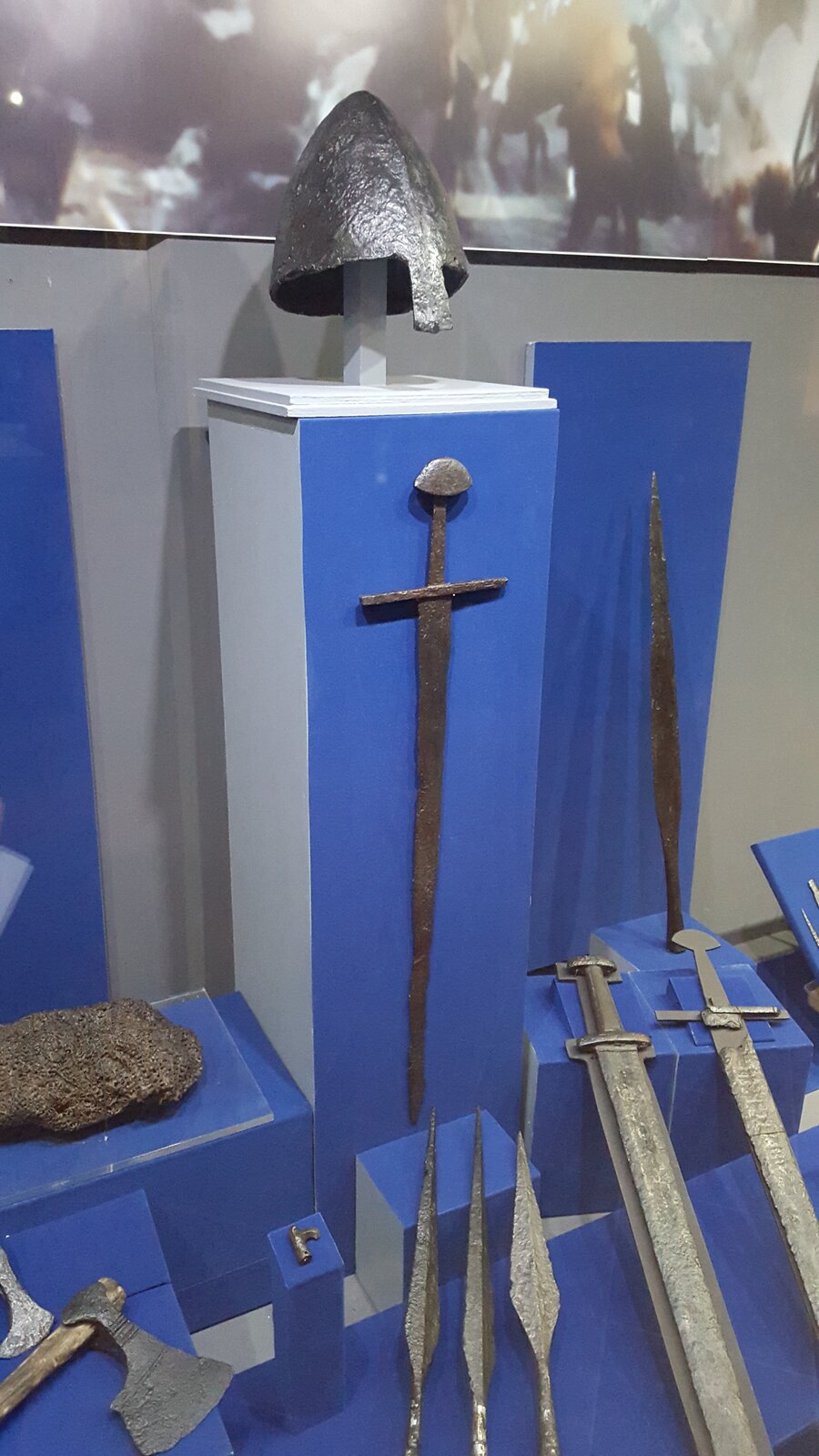 Na zdjęciu znajduję się wystawa ze średniowieczną bronią i uzbrojeniem. Znajdują się na niej liczne miecze, ostrza, groty i siekiery. 