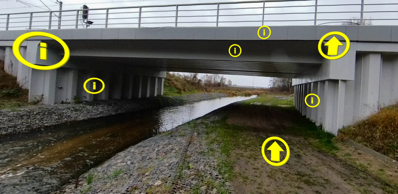 Przykładowy ekran w wycieczce. Na zdjęciu pokazany jest most ponad rzeką. Widoczne jest kilka symboli. Dwie żółte strzałki oraz pięć wykrzykników.