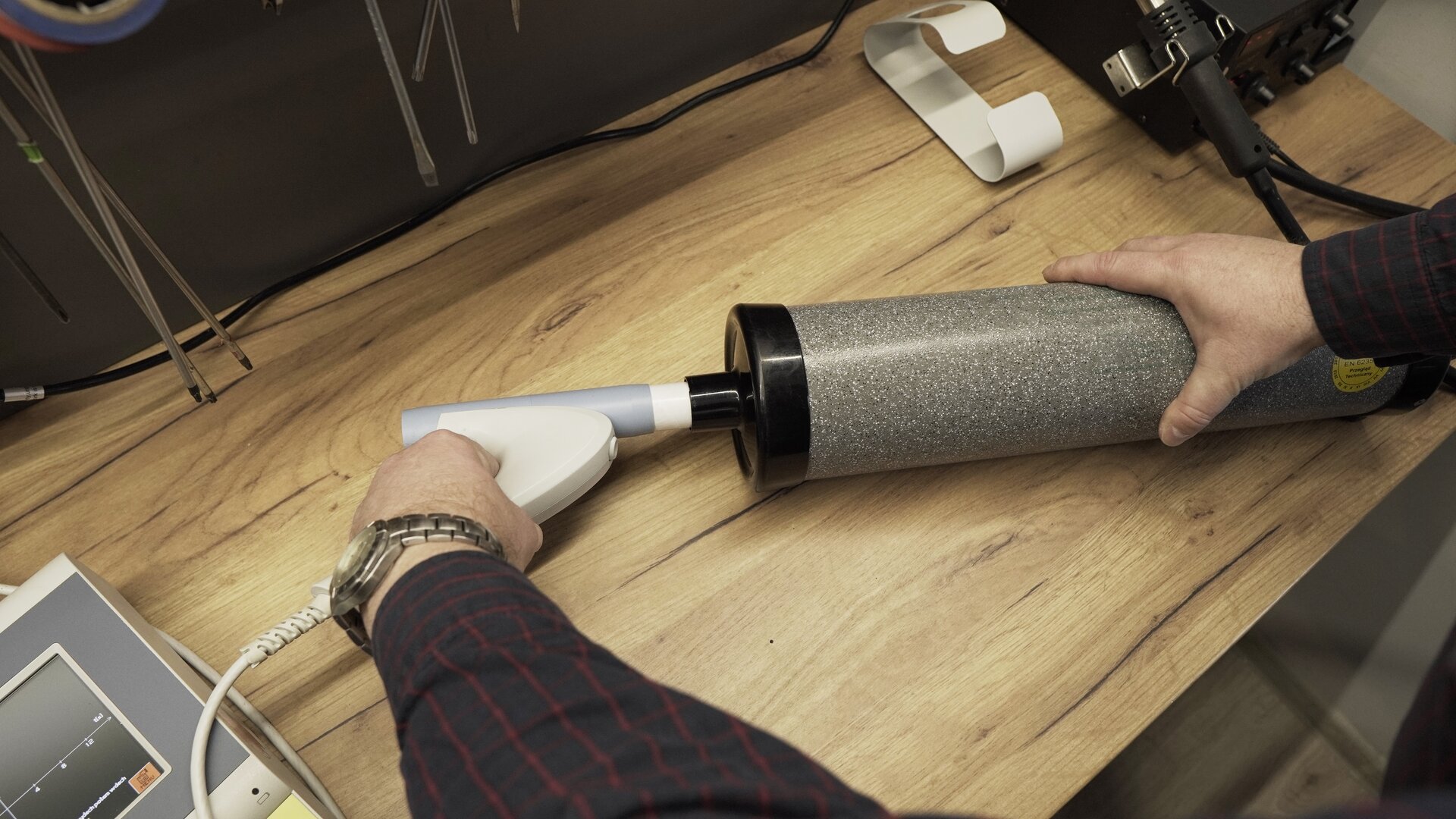 Na zdjęciu technik sprawdza szczelność podłączenia przetwornika z  pompą kalibracyjną. 