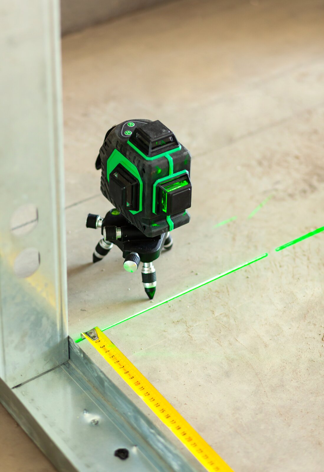 Ilustracja przedstawia niewielkie urządzenie na nóżkach. Za pomocą emitowanej wiązki laserowej możliwe jest ustalenie poziomu powierzchni. 