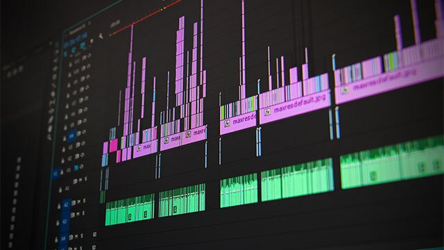 Na zdjęciu znajduje się ekran konsoli do obróbki dźwięku, na którym wyświetlają się różowe i zielone słupki audio przyporządkowane do kilku kategorii.