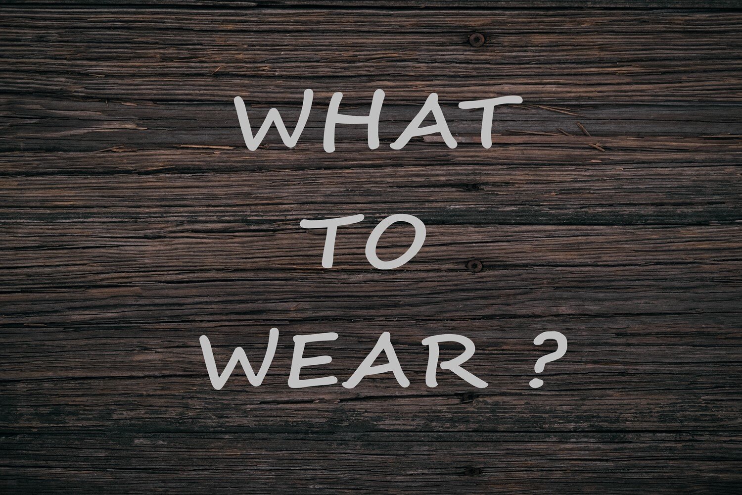 Ilustracja zawiera napis w języku angielskim WHAT TO WEAR.  Drukowane białe litery napisano na brązowym tle przypominający strukturą deski. 