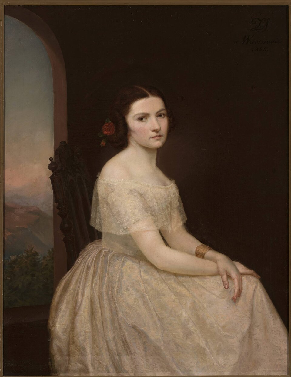 Obraz przedstawia młodą kobietę siedzącą na krześle. Postać ukazuje trzy czwarte okrągłej twarzy. Kobieta obraca głowę w swoją prawą stronę. Jej włosy są równo zaczesane na dwie strony i upięte. Prawy bok fryzury zdobi kwiat. Czoło kobiety jest dość niskie i gładkie. Ma ciemne włosy i zamyślone spojrzenie. Jej nos jest prosty, a policzki delikatnie zarumienione. Kobieta jest ubrana w długą suknię z dekoltem w kształcie łódki. Nadgarstek lewej ręki jest ozdobiony szeroką bransoletą. Ręce są skrzyżowane na kolanach.