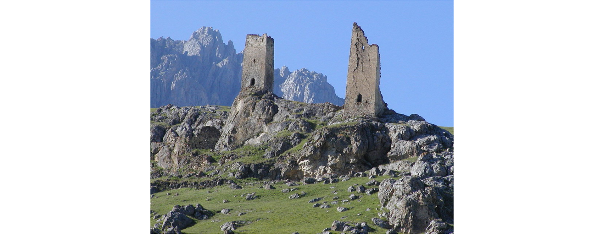 Ilustracja przedstawia ruiny dwóch wież na skalnych wzniesieniach.