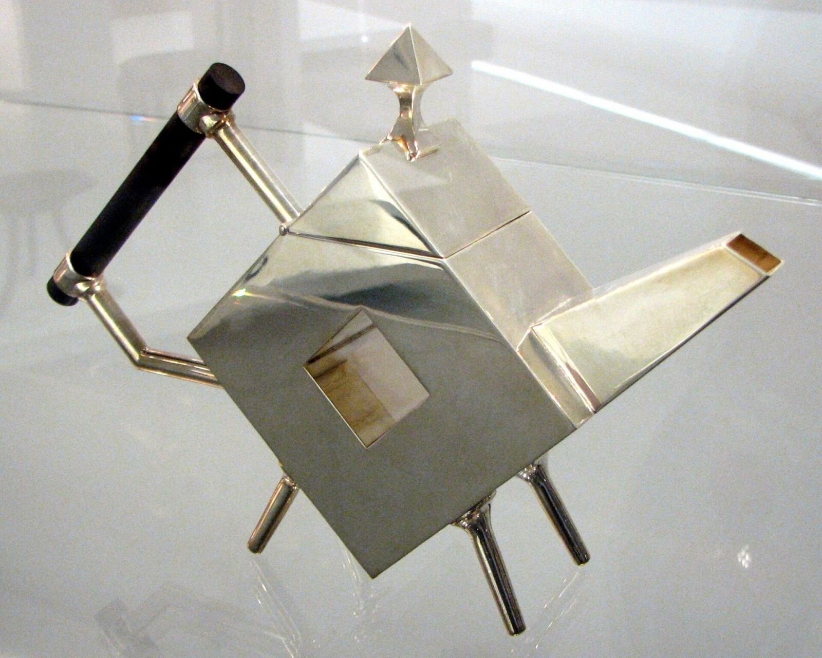 Ilustracja interaktywna przedstawia czajniczek zaprojektowany przez Christophera Dressera. Naczynie posiada niecodzienną kanciastą formę, cechują go geometryczne złote kształty. Projektant starał się uchwycić funkcjonalność rzeczy codziennego użytku wraz z ciekawym kształtem. 