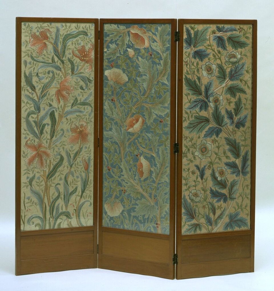 Ilustracja przedstawia pracę Johna Henry'ego Dearle'a - Morris &amp; Co. (manufacturer). Mężczyzna zasłynął z projektowania tkanin oraz witraży. Na fotografii widzimy przedmiot wyglądem przypominający parawan. Powstał on w latach 1885‑1910. Na jego ściankach znajdują się zdobienia kwiatowe. Obicie parawanu jest w kolorze brązowym.