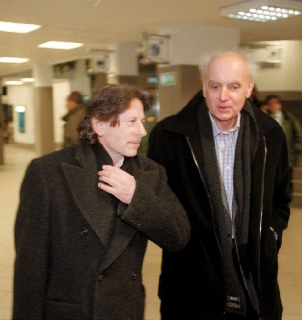 Fotografia przedstawia Wojciech Kilar z Romanem Polańskim, uchwyceni w obiektywie aparatu przez Roberta Krzanowskiego. Mężczyźni rozmawiają podczas spaceru. Mają delikatnie uśmiechnięte twarze. Ubrani są w ciemne płaszcze. Polański ma w prawej ręce teczkę skórzaną, natomiast Kilar trzyma ręce w kieszeni.