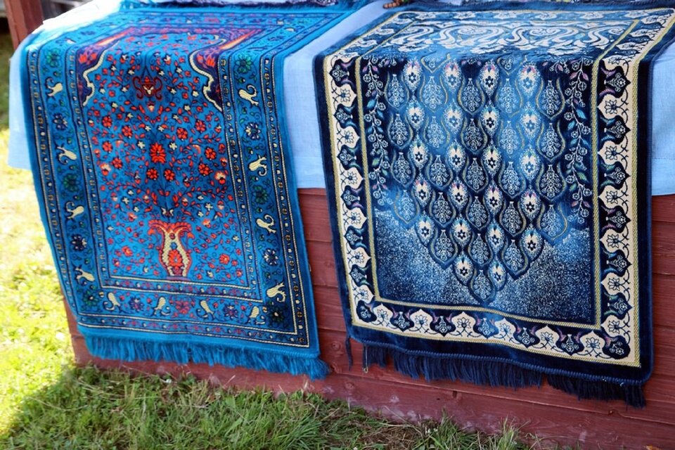 Ilustracja przedstawia ozdobne, niebieskie tapestry (tatarskie dywany) z licznymi ornamentami.