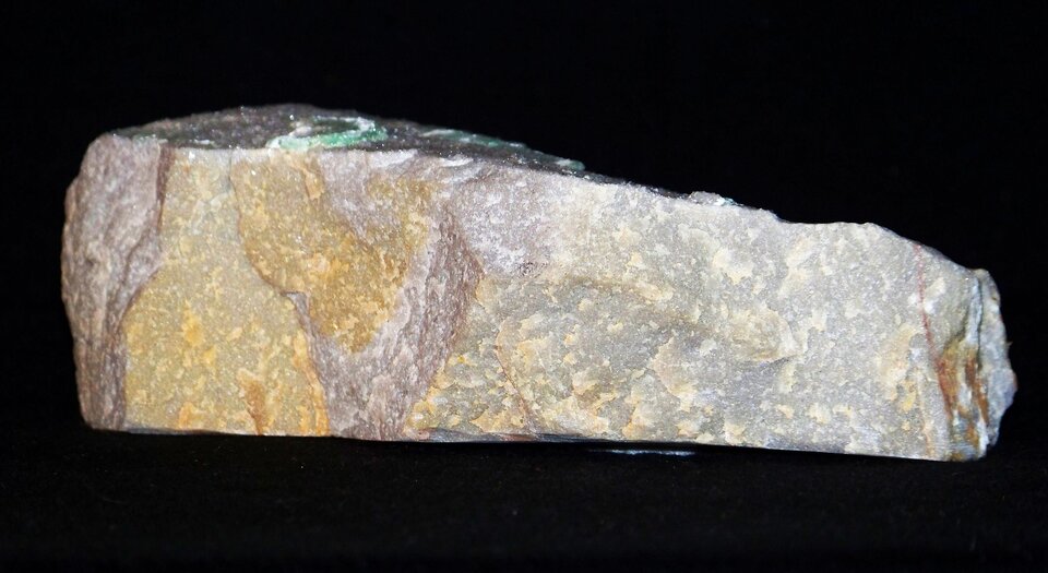 Zdjęcie przedstawia kwarcyt. Ma regularny prostokątny kształt. Jego powierzchnia jest chropowata o biało żółto brązowej barwie.