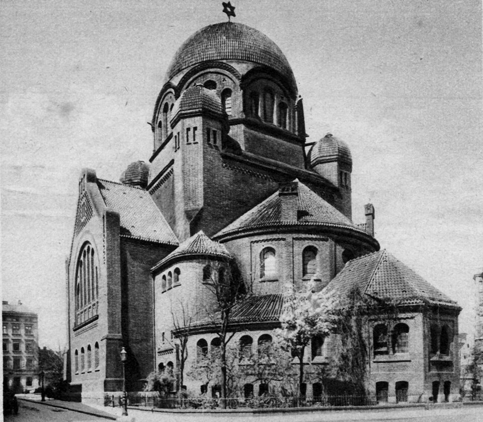 Fotografia przedstawia budynek złożony z kilku brył, najwyższy z nich ma na górze kopułę i gwiazdę Dawida na czubku.