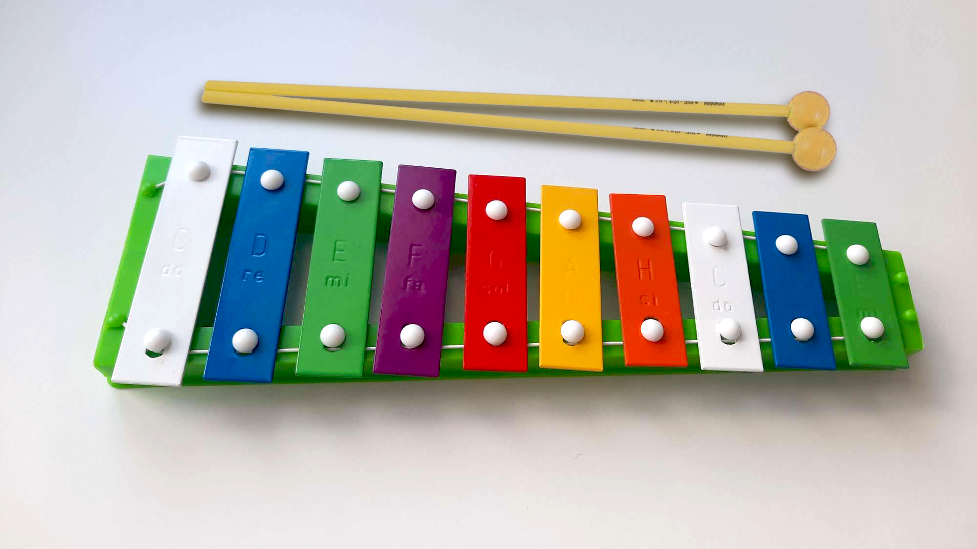 Zdjęcie przedstawia dzwonki chromatyczne. Jest to instrument muzyczny składający się z kolorowych blaszek przymocowanych do plastikowej podstawy. Każda blaszka ma inną długość, są one ułożone w kolejności od najdłuższej do najkrótszej. Do instrumentu są dołączone dwie drewniane pałeczki służące do uderzania w blaszki.