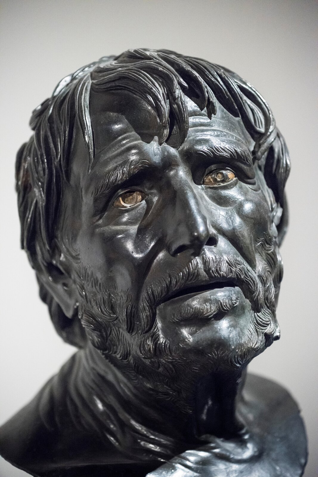 Ilustracja przedstawia rzeźbę „Pseudo-Seneka” autora nieznanego. Rzeźba ukazuje popiersie mężczyzny. Postać ma bujne włosy, wąsy i brodę. Mężczyzna ma smutny wyraz twarzy i patrzy na wprost z lekko otwartymi ustami.