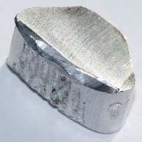 Ilustracja przedstawia bryłę aluminium, częściowo oszlifowaną i gładką, częściowo - z widocznymi nieregularnościami na powierzchni. 