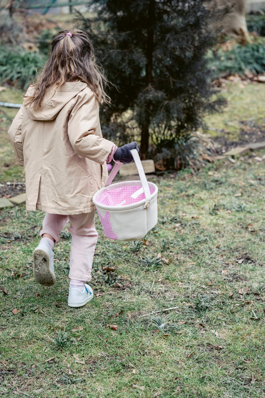 Ilustracja przedstawia kilkuletnią dziewczynkę. W ręku ma koszyczek idzie w kierunku krzewu wyraźnie czegoś szuka.