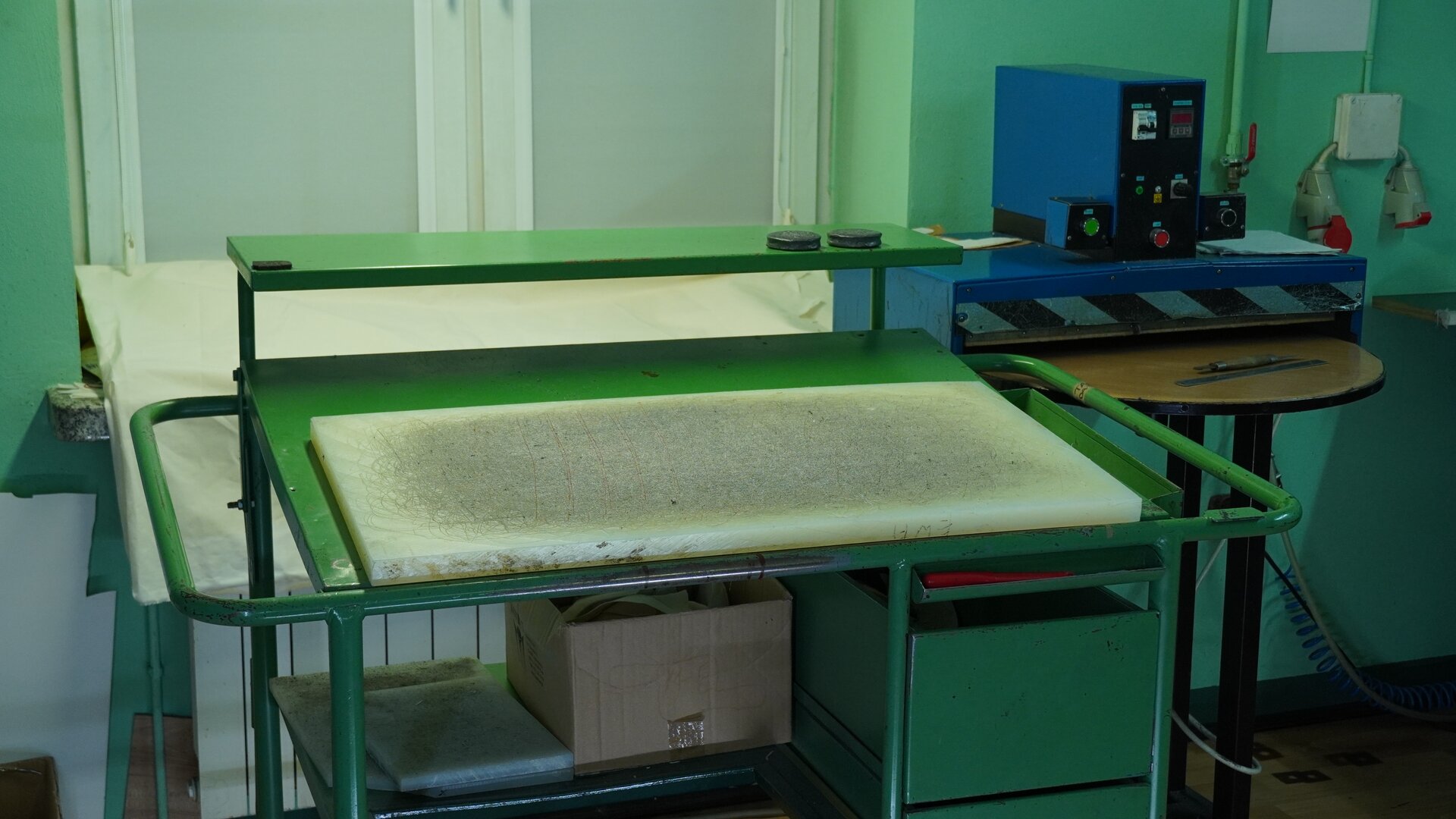 Zdjęcie przedstawia zielony metalowy stół, na którym znajduje się blat w jasnym kolorze. Nagranie tożsame z treścią.