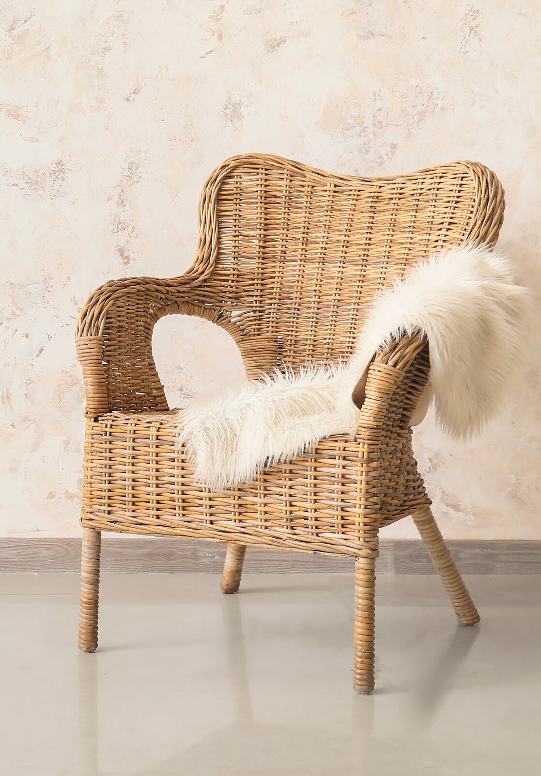 Zdjęcie fotela wiklinowego w jasnym kolorze. Fotel ma kształt fotela uszaka.
