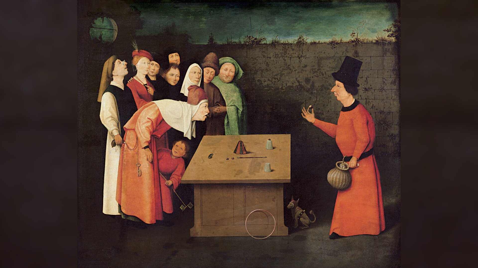 Obraz przedstawia grupę ludzi w średniowiecznych strojach, przypatrujących się stojącemu za stołem magikowi. Magik ubrany jest w czerwoną, długą szatę, na głowie ma wysoki kapelusz. W prawej ręce trzyma małą kulkę, a w lewej okrągły koszyk. Na stole leży kilka małych przedmiotów. Jeden z obserwujących pochyla się, aby lepiej dostrzec sztuczki magika.