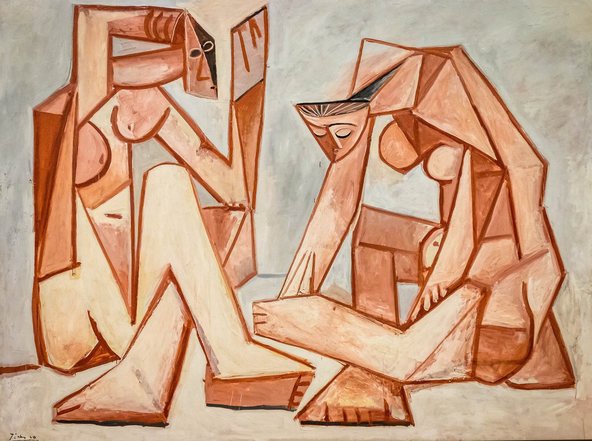 Ilustracja przedstawia obraz Pablo Picasso pt. „Kobiety nad morzem”. Na obrazie znajdują się dwie siedzące, nagie kobiety. Ich sylwetki złożone są z figur geometrycznych. W obrazie przeważają odcienie czerwieni oraz szarości.