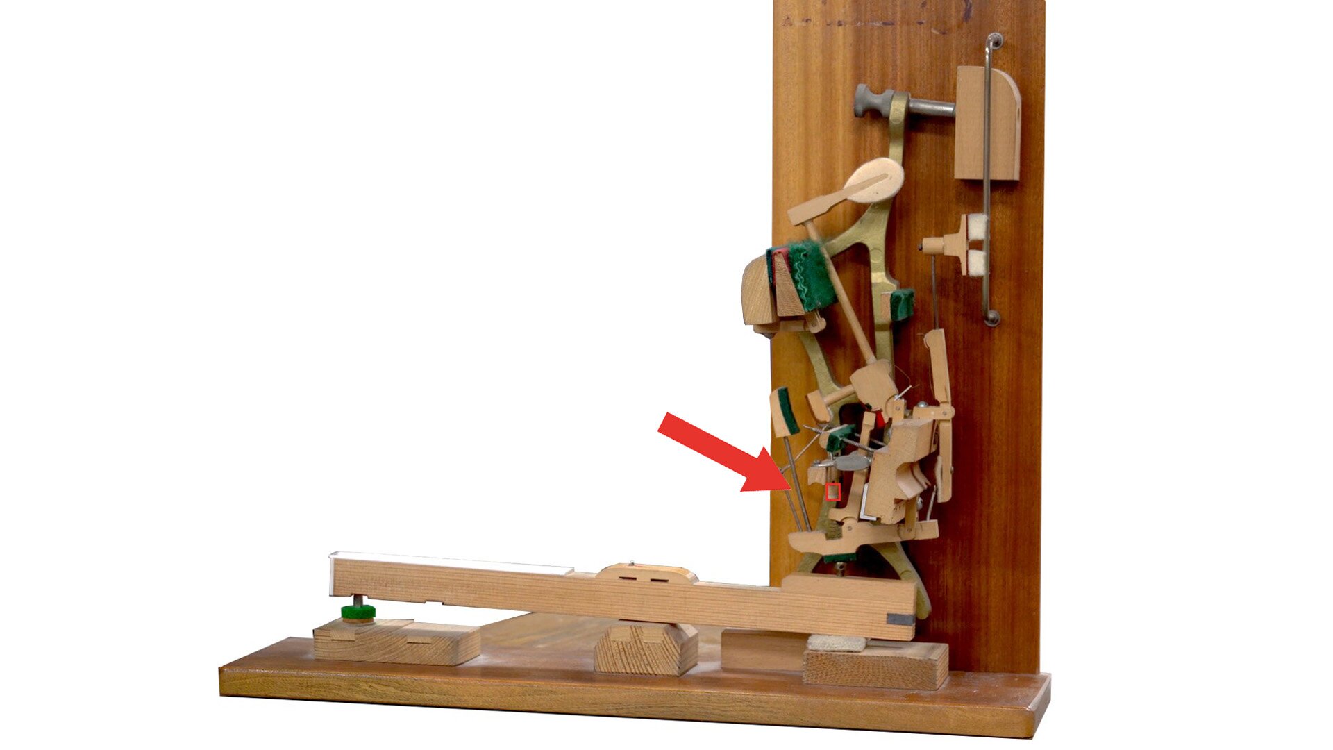 Zdjęcie przedstawia baryłkę wyzwalacza umieszczoną w mechanizmie pianinowym. Czerwona strzałka wskazuje jej lokalizację. 