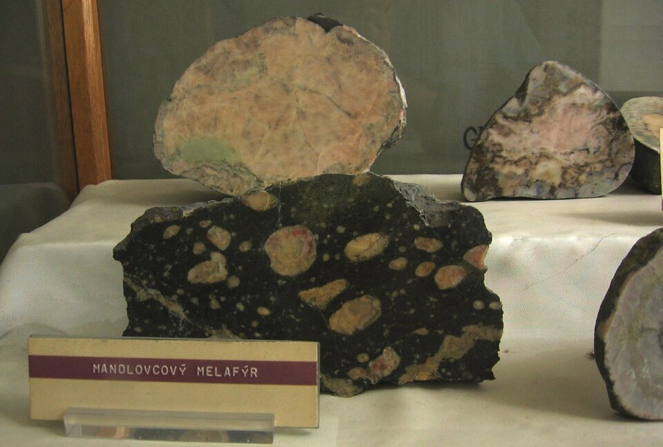 Zdjęcie przedstawia melafir. Posiada chropowatą powierzchnię oraz czarną barwę z białymi owalnymi kształtami.