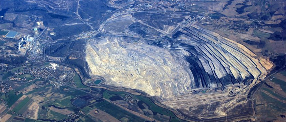 Panorama wyrobiska Kopalni Węgla Brunatnego Turów na Dolnym Śląsku, z widocznymi rekultywowanymi terenami, fragmentem odkrywki i zabudowaniami Elektrowni Turów, na tle pagórkowatego krajobrazu.