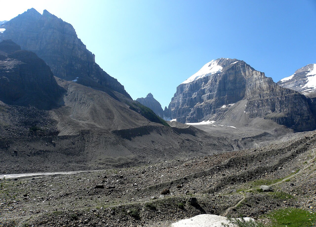 Zdjęcie przedstawia teren górski z wysokimi szczytami. U podnóża gór jest spora ilość materiału skalnego, który tworzy wały.
