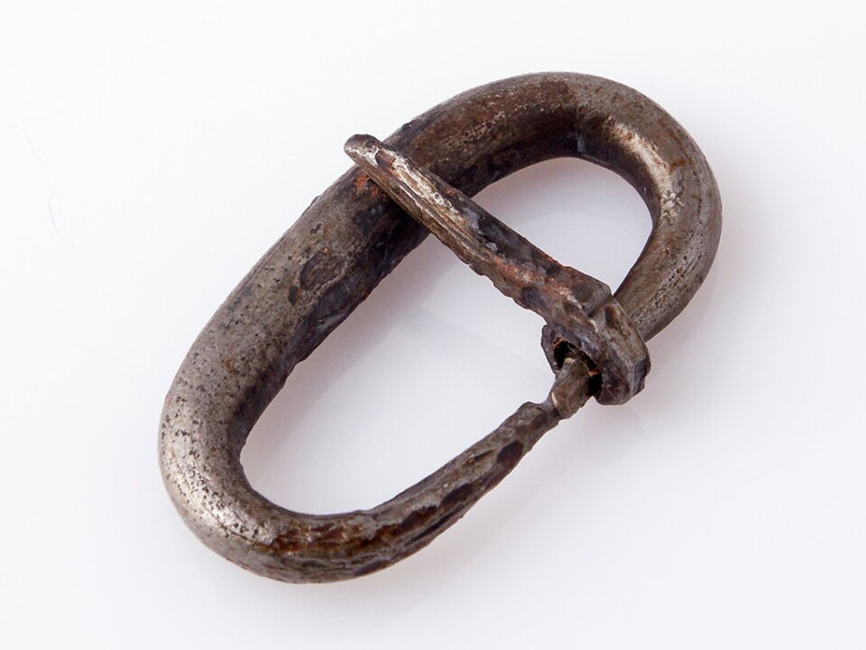 Ilustracja przedstawia sprzączkę żelazną do pasa. Ma ona eliptyczny kształt, a przez jej górną cześć przebiega zapięcie. 