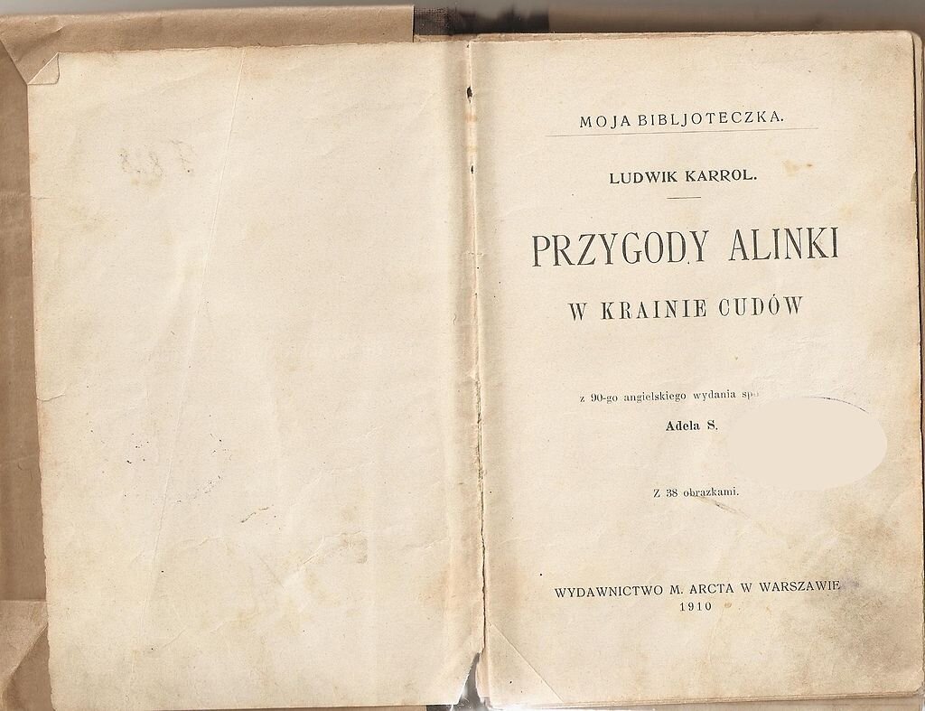 Zdjęcie podniszczonej, pożółkłej książki otwartej na stronie tytułowej. Widoczne napisy – od góry: Moja Bibljoteczka, Ludwik Karrol, Przygody Alinki w Krainie Cudów, z 90‑tego angielskiego wydania spo (zamazana reszta słowa), Adela S., z 38 obrazkami, Wydawnictwo M. Arcta w Warszawie, 1910.
