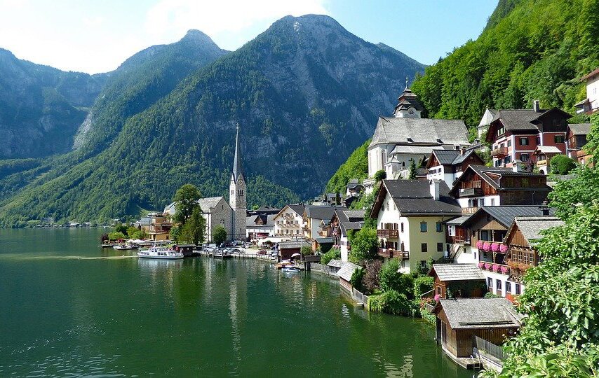 Na fotografii przedstawiono górskie jezioro Hallstätter. Widoczny jest zielony odcień wody jeziora wspaniale współgrający z kolorem roślinności na ścianach skalnych wychodzących z jeziora. Na prawym brzegu jeziora widać zabudowania miejscowości robiąc wrażenie bajkowych swoją wyjątkowo alpejska architekturą. Dachy domów są spadziste, a na balkonach jest bardzo dużo kwiatów. Do tego dochodzą zabytkowe kościoły ze strzelistymi wieżami.