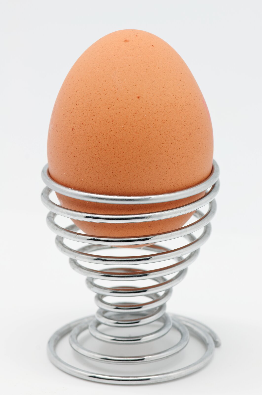 Zdjęcie przedstawia jajko stojące w metalowym kieliszku.