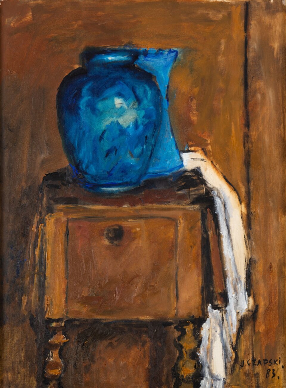 Józef Czapski, „Niebieskie wazony”. Obraz przedstawia dwa niebieskie wazony oraz biały materiał umieszczone na niewielkiej drewnianej szafce z okrągłą gałką i ozdobnymi nóżkami. Tło stanowi mebel o podobnym, brązowym odcieniu drewna. Wazon ukazany z przodu jest szeroki, a jego koniec zwęża się. Jest intensywnie niebieski, delikatnie odbija światło. Za nim stoi drugi niebieski wazon, nieco jaśniejszy. Zwęża się w okolicy środka swojej wysokości, a następnie znów rozszerza, tworząc kształt łuku. Za nim, zwisając w stronę podłogi, znajduje się biały materiał. W prawym dolnym rogu umieszczono czarny podpis „J. CZAPSKI. 83.”