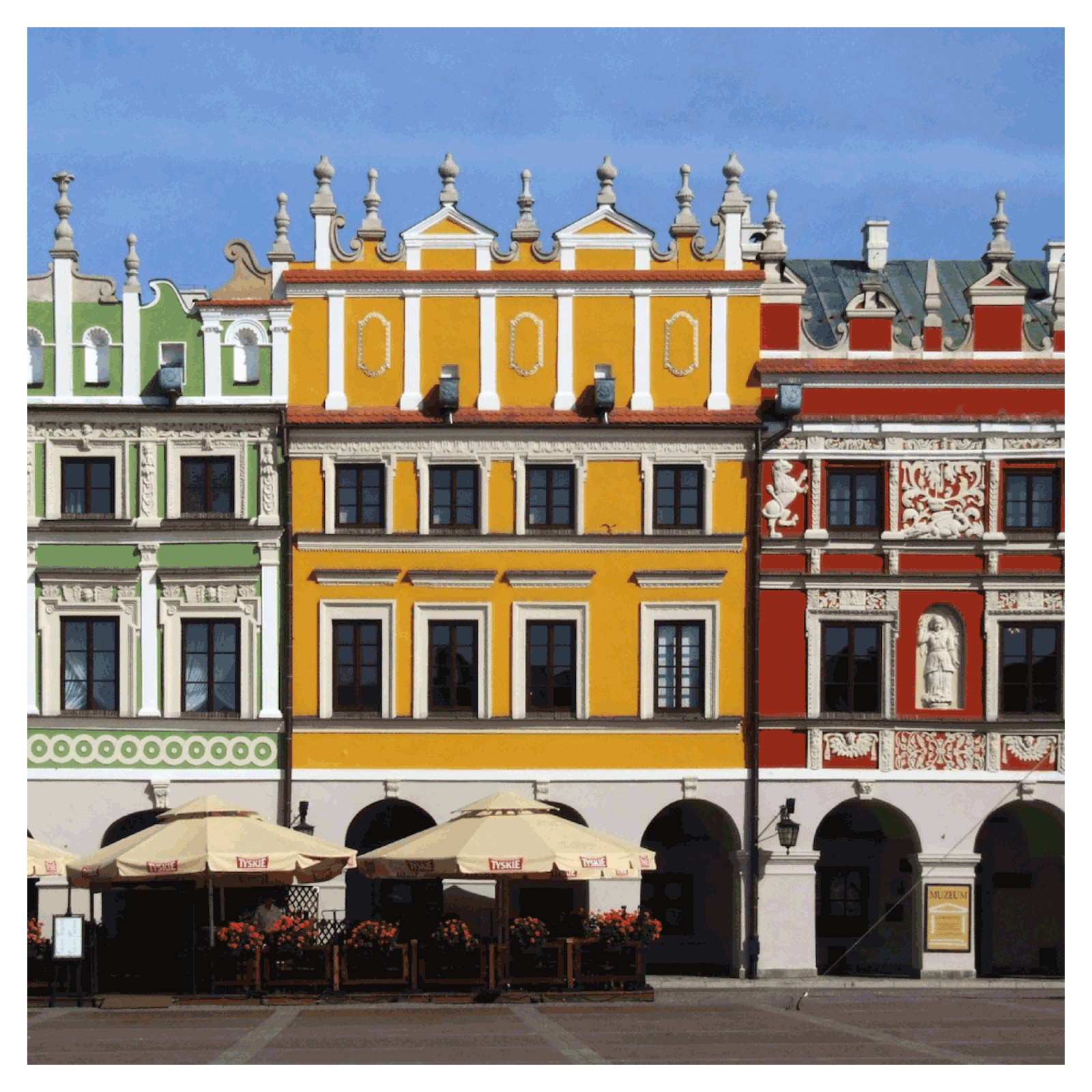 Zdjęcie przedstawia niskie, czterokondygnacyjne kamienice. Każda ma inny kolor: zielony, żółty, czerwony. Na górze kamienic są wieżyczki. 