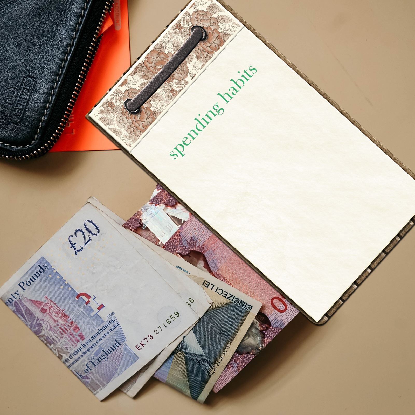 Zdjęcie przedstawia blat stołu, na którym leżą banknoty brytyjskie i podkładka na dokumenty, na której znajduje się kartka z napisem spending habits. W lewym górnym rogu jest widoczny fragment czarnego portfela.